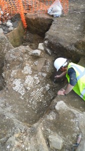Resti di pavimento a mosaico romano sono attentamente rivelati. Dopo la demolizione dell'edificio, il pavimento è stato rotto ed è crollato giù per una delle trincee vuote delle fondamenta. Credit: University of Leicester