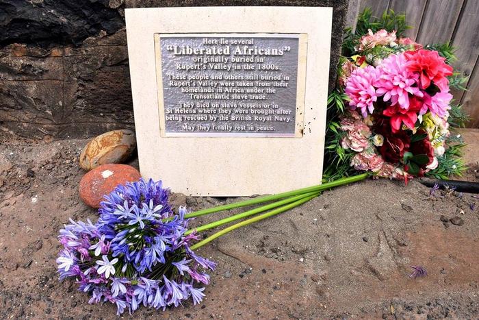 A plaque dedicated to "Liberated Africans" in St. Helena with flowers around it. Credits: St Helena Government, CC BY-SA
