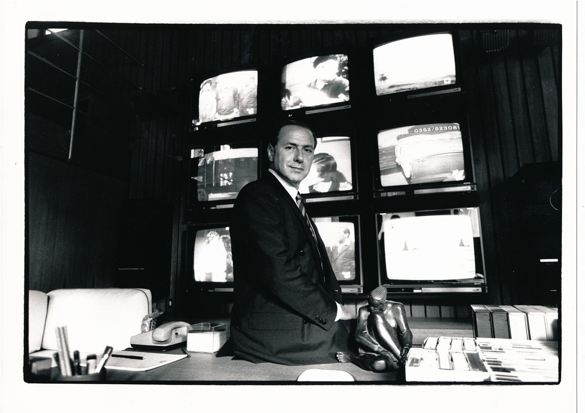 © Archivio Pino Granata Berlusconi davanti a colonna televisori (b/n)