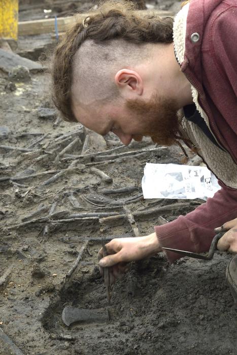 A member of the Cambridge Archaeological Unit uncovering an axe head during excavations at the Must Farm site in 2016. 