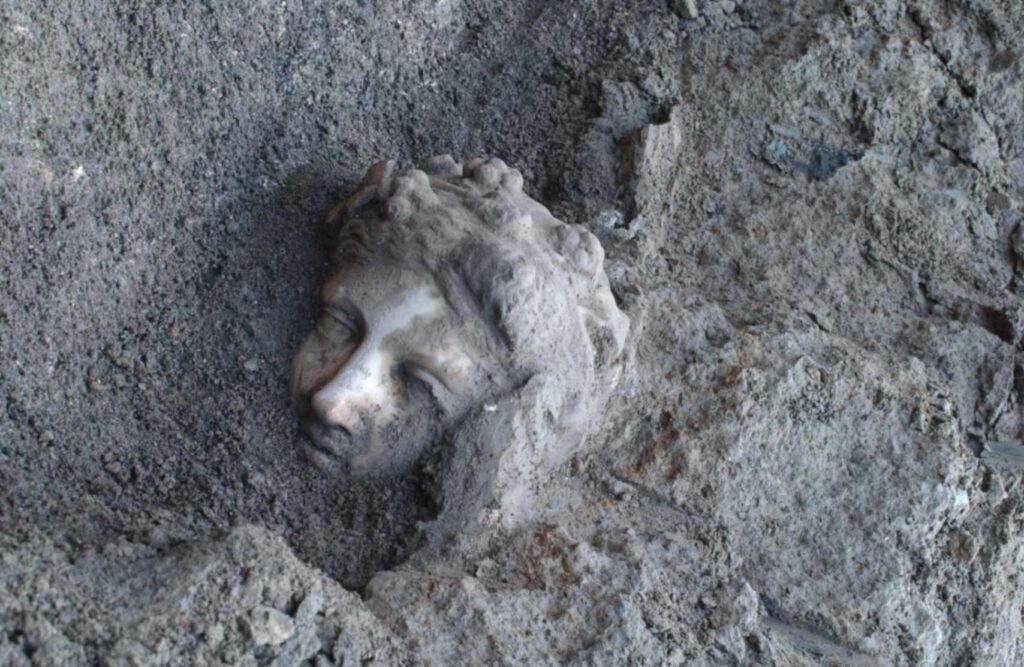 A face from history. A haunting sight at the archaeological site. The face of a statue of the god Dionysus as it’s painstakingly chipped away from and brushed free of millennia of built-up deposits. ©2024 Institute for Advanced Global Studies CC-BY-ND