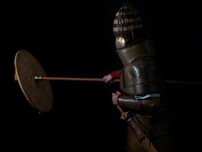 Dendra armour in combat Man wearing replica armour and hitting a sheild with a spear/staff.